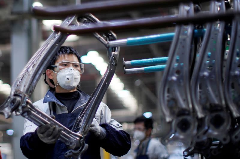 FILE PHOTO: Employee wearing a face mask works on a car seat assembly line at Yanfeng Adient factory in Shanghai