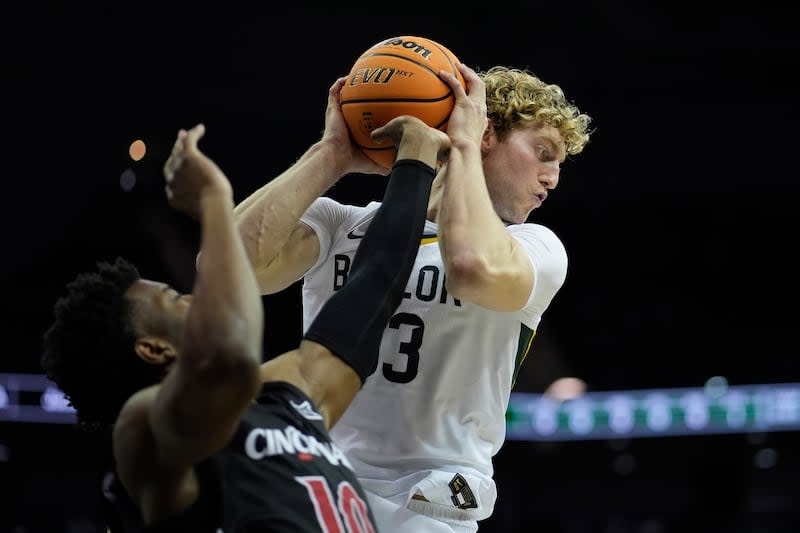 Cincinnati guard Josh Reed (10) tries to knock the ball away from Baylor forward Caleb Lohner, top, during the first half of an NCAA college basketball game in the quarterfinal round of the Big 12 Conference tournament, Thursday, March 14, 2024, in Kansas City, Mo. | Charlie Riedel