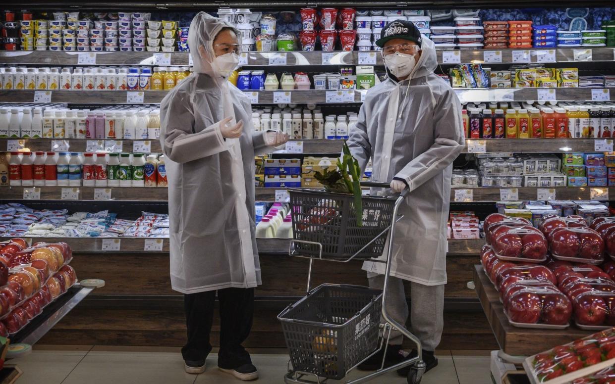 A Chinese couple wear plastic coats and protective masks  - Kevin Frayer /Getty Images AsiaPac 