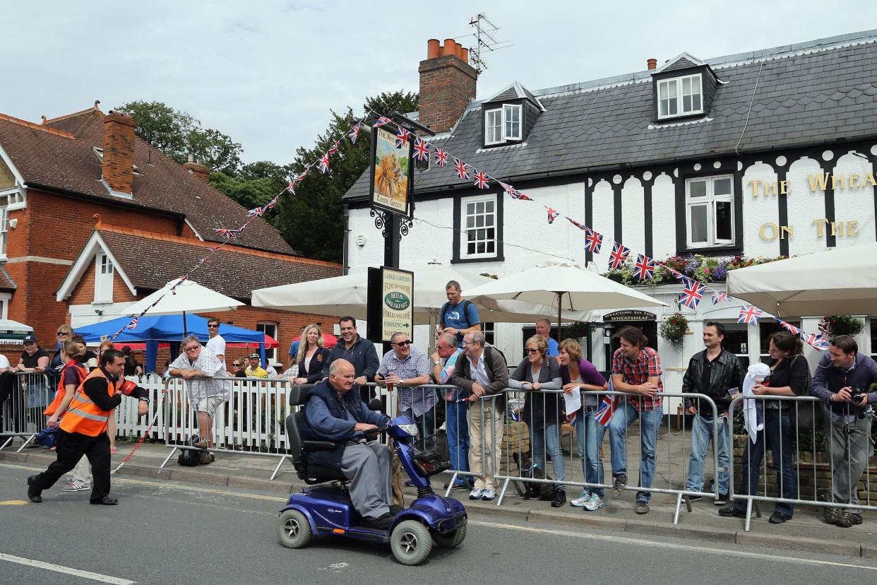 An official chases a man on a mobility scooter as he attempts to drive down the cycle route ahead of the Men's Individual Time Trial Road Cycling on day 5 of the London 2012 Olympic Games on August 1, 2012 in London, England