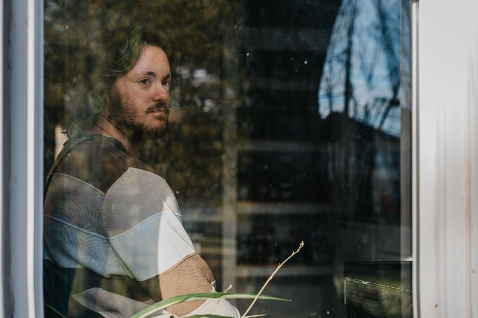 Sam Guido looks out a window at his home.