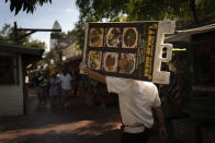 Restaurant worker Abraham Ordaz, 38, carries a menu stand along Olvera Street in Los Angeles, Tuesday, June 8, 2021. Olvera Street has long been a thriving tourist destination and a symbol of the state's early ties to Mexico. The location of where settlers established a farming community in 1781 as El Pueblo de Los Angeles, its historic buildings were restored and rebuilt as a traditional Mexican marketplace in 1930s. As Latinos in California have experienced disproportionately worse outcomes from COVID-19, so too has Olvera Street. (AP Photo/Jae C. Hong)
