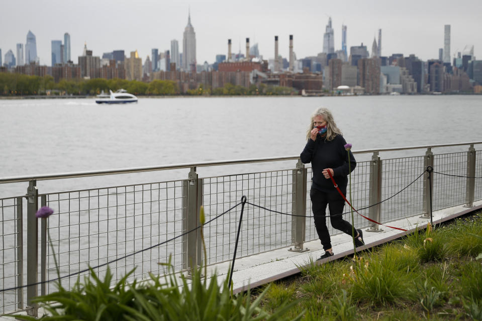 A jogger adjusts her face mask as she passes through Domino Park, Friday, May 8, 2020, in the Brooklyn borough of New York. Some parks will see stepped-up policing to stem the spread of the coronavirus, New York City Mayor Bill de Blasio said Friday. He also announced that 2,500 members of a "test and trace corps" will be in place by early June to combat the virus. (AP Photo/John Minchillo)