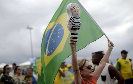 A demonstrator carries a Brazilian national flag and holds an inflatable doll known as "Pixuleco" of Brazil's former president Luiz Inacio Lula da Silva during a protest against Brazil's President Dilma Rousseff, part of nationwide protests calling for her impeachment, at Copacabana beach in Rio de Janeiro, Brazil, March 13, 2016. REUTERS/Ricardo Moraes