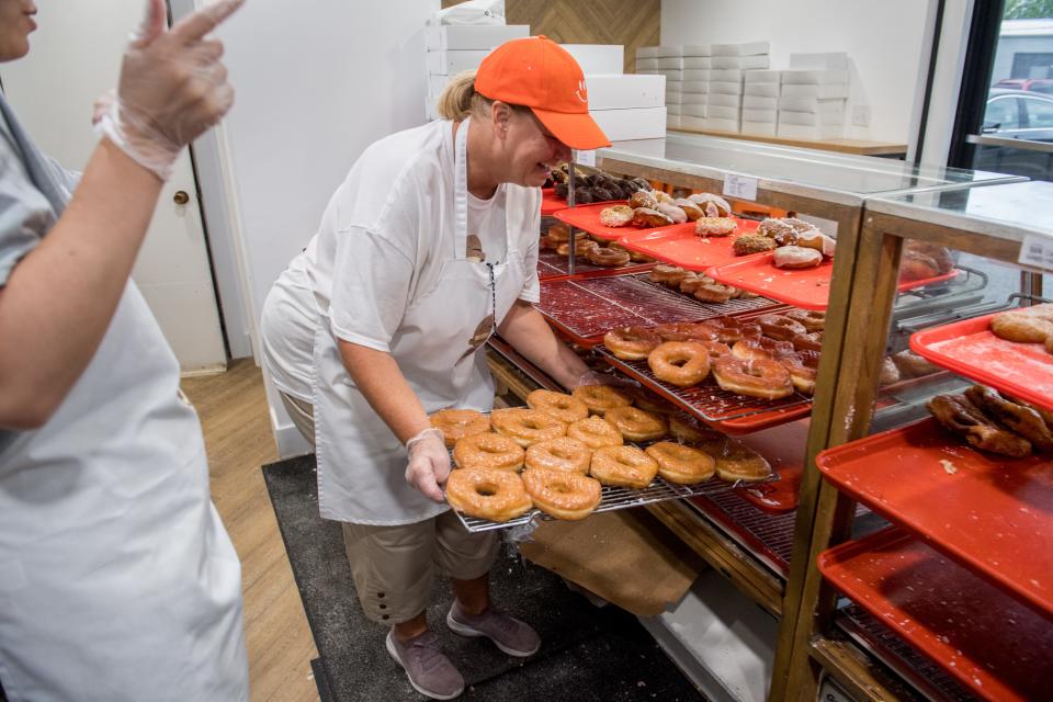 Tammy Hicks refills a rack of glazed doughnuts in the case at the new Tadoughs, formerly Spudnuts, in Pekin.