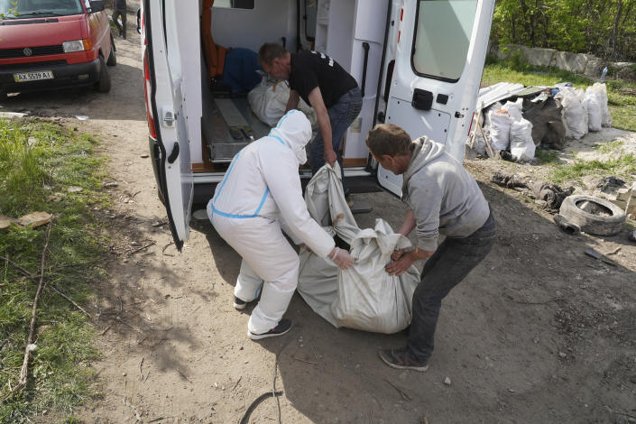 Volunteers move a body of a killed Russian soldier during the exhumation in the village of Malaya Rohan, on the outskirts of Kharkiv, Thursday, May 19, 2022. (AP Photo/Andrii Marienko)