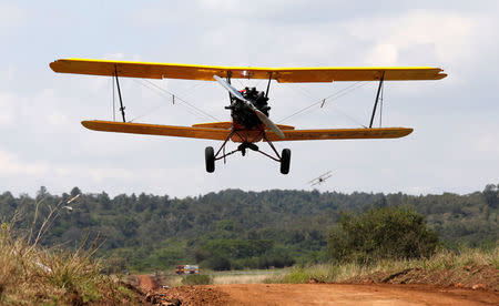 A biplane flies over a dirt road used as a makeshift runway during the Vintage Air Rally at the Nairobi national park in Kenya's capital Nairobi, November 27, 2016. REUTERS/Thomas Mukoya