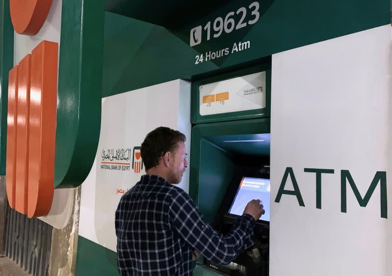 FILE PHOTO: A man withdraws money from an ATM machine at the National Bank of Egypt (NBE) in Cairo