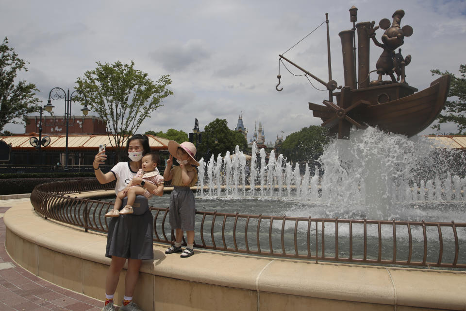 Visitors take photos outside the Disney Resort theme park, Thursday, June 30, 2022, in Shanghai. Shanghai is moving to allow in-person dining and reopening its Disney Resort theme park as domestically transmitted cases of COVID-19 in China's largest city remain at zero following a more than two-month lockdown. (AP Photo/Chen Si)