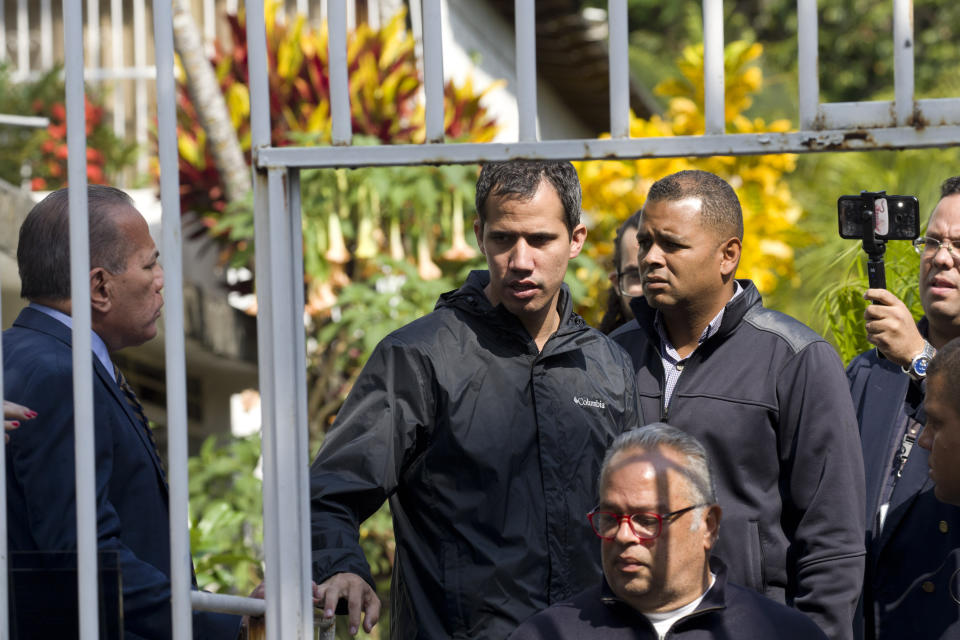 In this March 21, 2019 photo, Venezuelan opposition leader Juan Guaido stands near a gate at the home of top aide Roberto Marrero, in Caracas, Venezuela. Marrero was taken away by intelligence agents in an overnight operation on his home early Thursday. Guaido characterized the operation as a sign that Nicolas Maduro is losing his grip on power. (AP Photo/Ariana Cubillos)