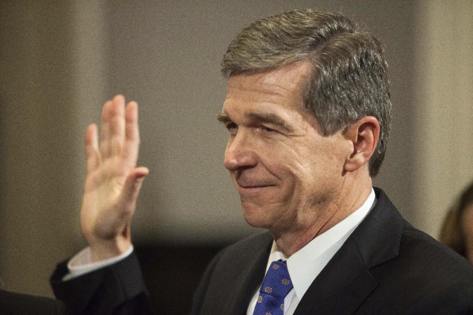 File-In this Jan. 1, 2017 photo Roy Cooper is sworn in as North Carolina governor shortly after midnight at the historic state Capitol Building in Raleigh, N.C. In politically divided North Carolina, weary voters hope top elected officials can put aside differences and effectively govern after a bruising election and a partisan tug-of-war that has spilled into court. (AP Photo/Ben McKeown, Pool)
