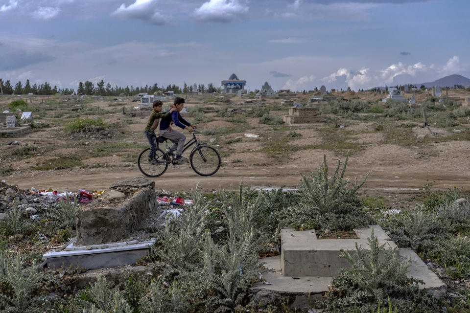 Afghan boys ride a bicycle at a cemetery in Kabul, Afghanistan, Wednesday, May 4, 2022. There are cemeteries all over Afghanistan's capital, Kabul, many of them filled with the dead from the country's decades of war. They are incorporated casually into Afghans' lives. They provide open spaces where children play football or cricket or fly kites, where adults hang out, smoking, talking and joking, since there are few public parks. (AP Photo/Ebrahim Noroozi)