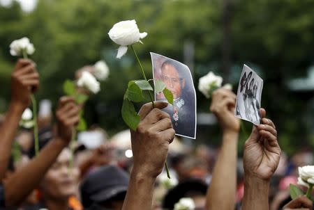 People hold General Aung San's portrait and flowers as they wait to pay respect during an event marking the anniversary of Martyrs' Day outside the Martyrs' Mausoleum in Yangon July 19, 2015. REUTERS/Soe Zeya Tun