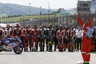 Teammates of 19 years-old Swiss pilot Jason Dupasquier and Moto3 pilots stand near his motorbike as they pay a minute of silence in his memory prior to the start of the Motogp Grand Prix of Italy at the Mugello circuit, in Scarperia, Italy, Sunday, May 30, 2021. Dupasquier died Sunday after being hospitalized Saturday, at the Florence hospital following his crash during the qualifying practices of the Moto3. (AP Photo/Antonio Calanni)