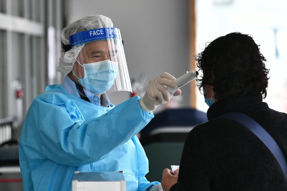 A medical worker wearing protective gear (L) takes the temperature of a woman as she enters Princess Margaret Hospital in Hong Kong on February 4, 2020. - Hong Kong on February 4 become the second place outside of the Chinese mainland to report the death of a patient being treated for a new coronavirus that has so far claimed more than 400 lives. (Photo by Anthony WALLACE / AFP) (Photo by ANTHONY WALLACE/AFP via Getty Images)