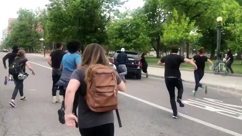 Protesters run after a vehicle speeding through a protest held in Denver held following the death of George Floyd in Minneapolis