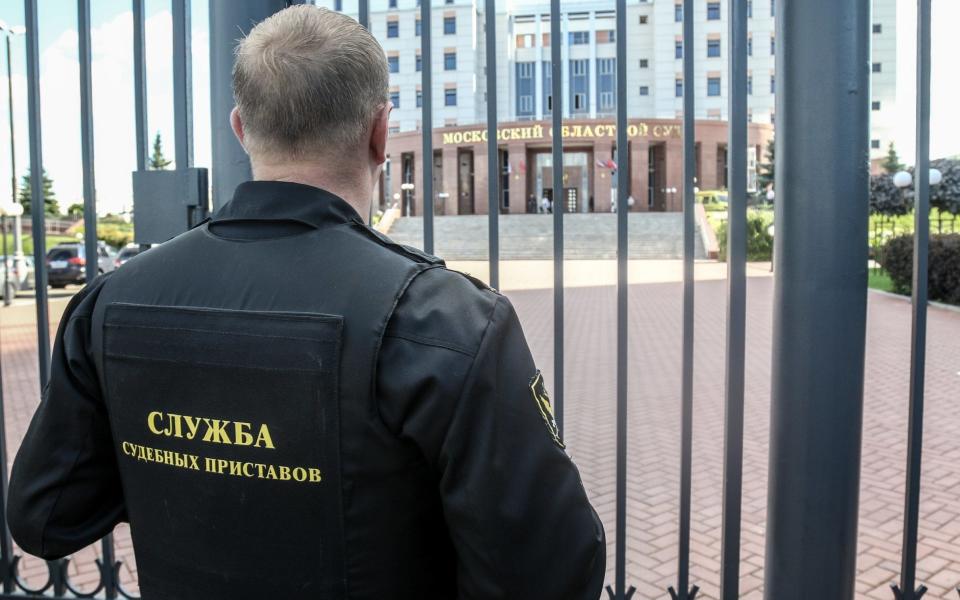 A bailiff stands behind a fence at the main entrance of Moscow Regional Court - Credit: Andrey Nikerichev/Moscow News Agency