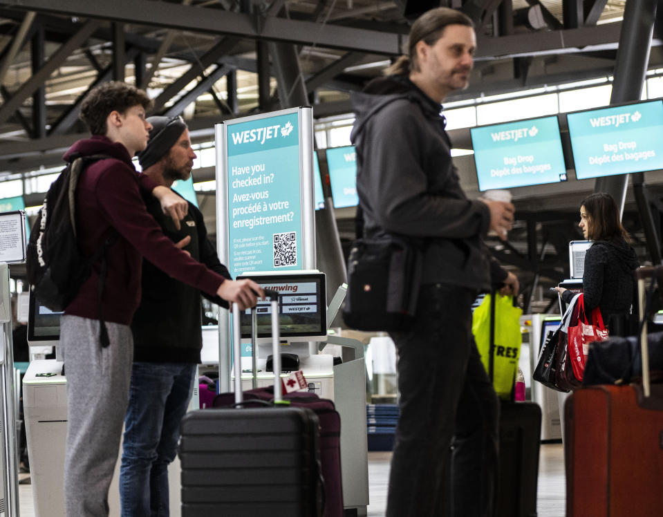 Travelers line up at the Ottawa International Airport, as airlines cancel or delay flights during a major storm in Ottawa, on Friday, Dec. 23, 2022. (Justin Tang /The Canadian Press via AP)