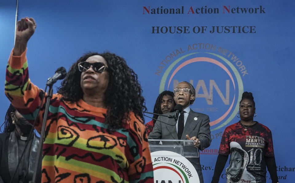 Kathy Jordan, far left, raise a fist as she sings with the National Action Network (NAN) ensemble during a rally commemorating the 10th anniversary of Trayvon Martin's killing, while his mother Sybrina Fulton, far right, his brother Jahvaris Fulton, second from left, join Rev. Al Sharpton on stage, Saturday Feb. 26, 2022, at National Action Network's Harlem headquarters in New York. (AP Photo/Bebeto Matthews)