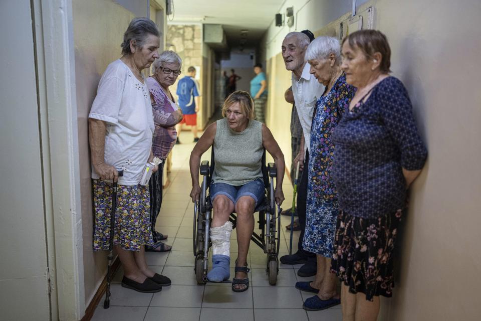 People wait to visit medics from the Ukrainian Red Cross at the center for displaced persons near Mykolaiv, Kharkiv region, Ukraine, Monday, Aug. 8, 2022. Ukraine's health care system already was struggling due to corruption, mismanagement and the COVID-19 pandemic. But the war with Russia has only made things worse, with facilities damaged or destroyed, medical staff relocating to safer places and many drugs unavailable or in short supply. (AP Photo/Evgeniy Maloletka)