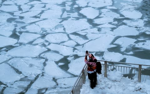 A pedestrian stops to take a photo by Chicago River as bitter cold phenomenon called the polar vortex has descended on much of the central and eastern United States - Credit: &nbsp;REUTERS