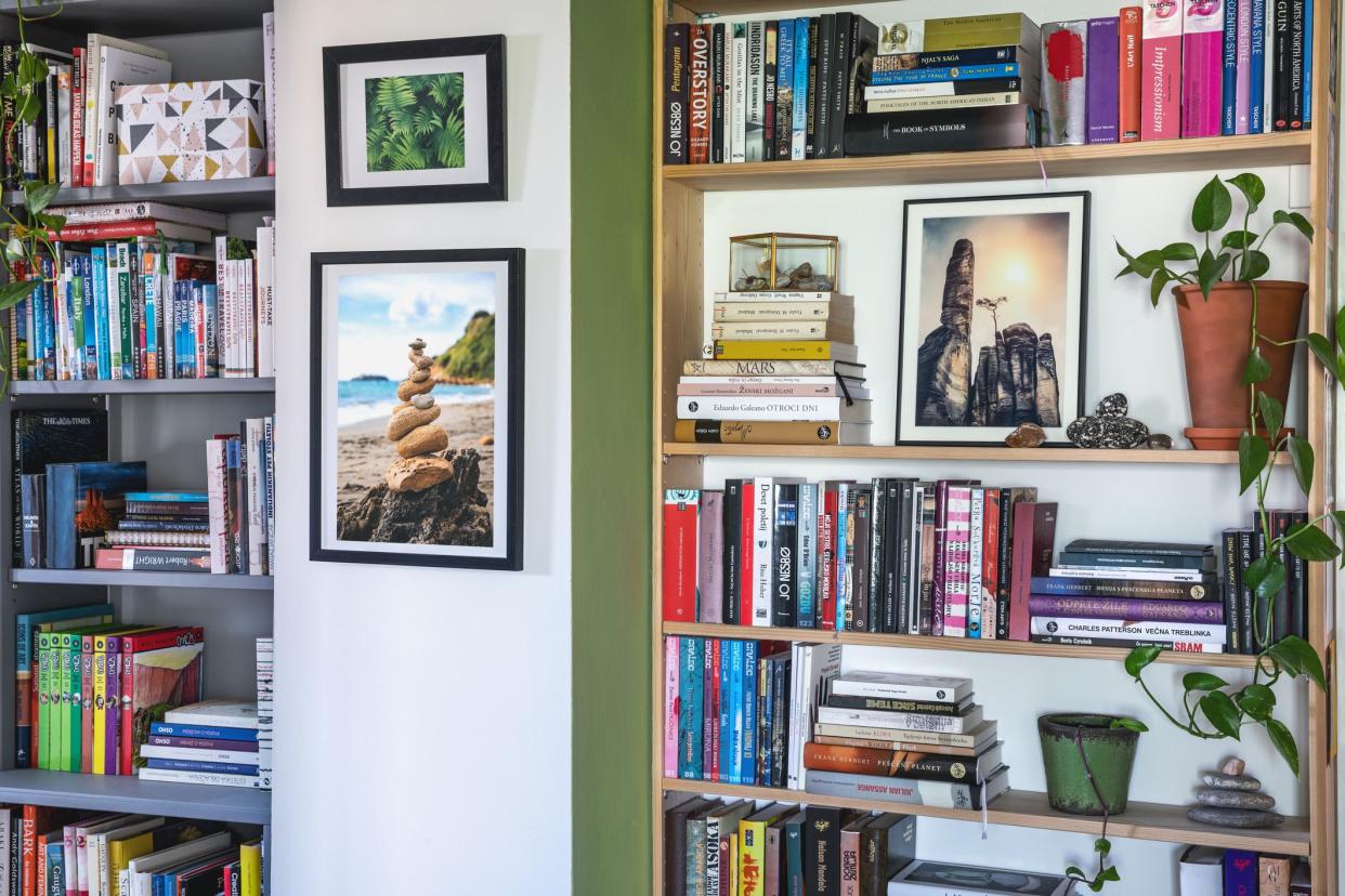 Wooden book shelves full of books, plants and photos.