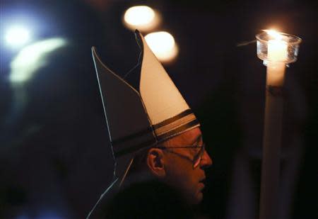 Pope Francis holds a candle as he leads a vigil mass during Easter celebrations at St. Peter's Basilica in the Vatican April 19, 2014. REUTERS/Alessandro Bianchi