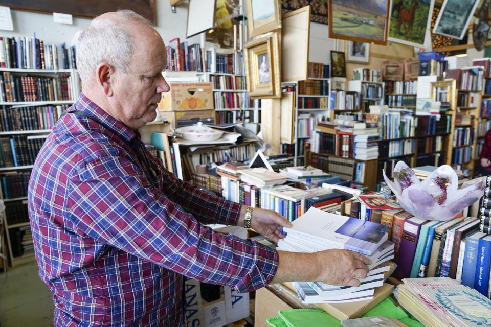 At a second-hand bookstore Thorvaldur Mariuson displays the former best-selling government report, known locally as "The Report", analysing the reasons for Iceland's enormous bank crash, in Reykjavik, Iceland, Sunday Oct. 7, 2018. On the 10-year anniversary of the financial crash, now known as “hrunid”, the collapse, the last in a series of prosecutions of those deemed responsible has started, and Icelanders look for some closure after years of reckoning and reconstruction. (AP Photo/Egill Bjarnason)