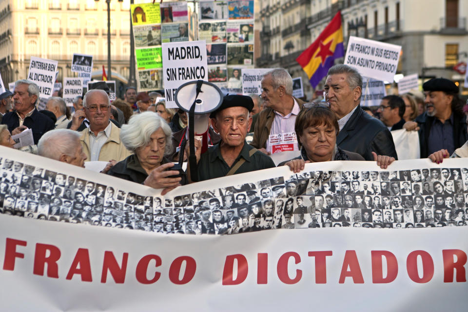 Protesters march behind a banner reading 'Franco Dictator' in Madrid, Spain, Thursday Oct. 25, 2018.Hundreds of protesters in Madrid are urging government and Catholic church authorities to prevent the remains of the country’s 20th century dictator from ending in the city’s cathedral. Spain’s center-left government has promised to exhume this year Gen. Francisco Franco from a glorifying mausoleum, but the late dictator’s heirs have defied the plans by proposing for his remains to be relocated to a family crypt under the cathedral. (AP Photo/Paul White)