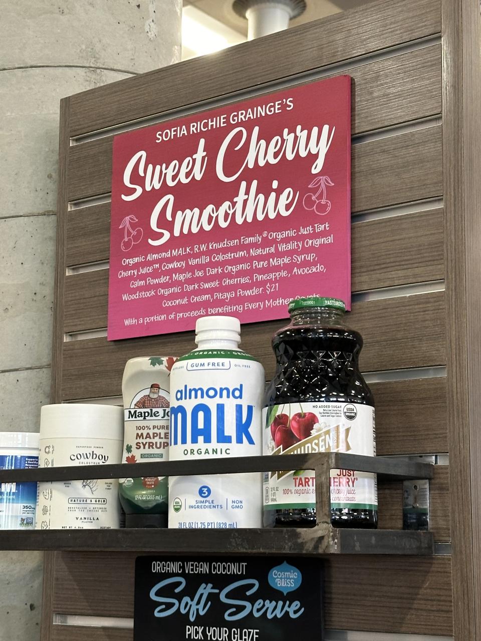 Shelf with various organic food products under a pink sign reading "SOFIA RICHIE GRAINGE'S Sweet Smoothie Cherry Smoothie."