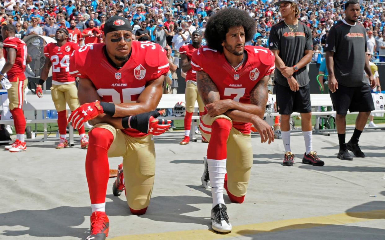 Colin Kaepernick (7) and Eric Reid (35) kneel during the national anthem before an NFL football game against the Carolina Panthers - FR34342 AP