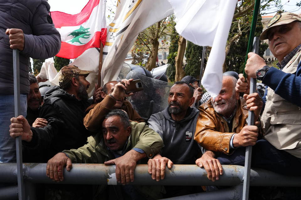 Retired members of the Lebanese security and other protesters try to remove a gate in order to advance towards the government building, background, during a protest demanding better pay in Beirut, Lebanon, Wednesday, March 22, 2023. Lebanese security forces fired tear gas to disperse hundreds of protesters who tried to break through the fence leading to the government headquarters in downtown Beirut Wednesday amid widespread anger over the harsh economic conditions in the country. (AP Photo/Hassan Ammar)