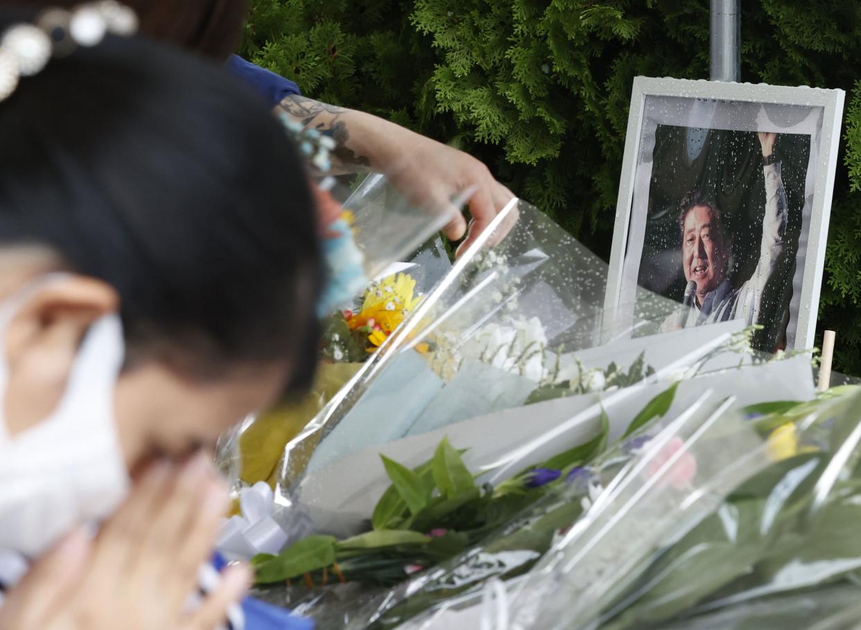 A photo of former Prime Minister Shinzo Abe is displayed on a makeshift memorial near the scene where Abe was fatally shot while delivering his speech to support a Liberal Democratic Party's candidate on Friday, in Nara, Saturday, July 9, 2022. 
