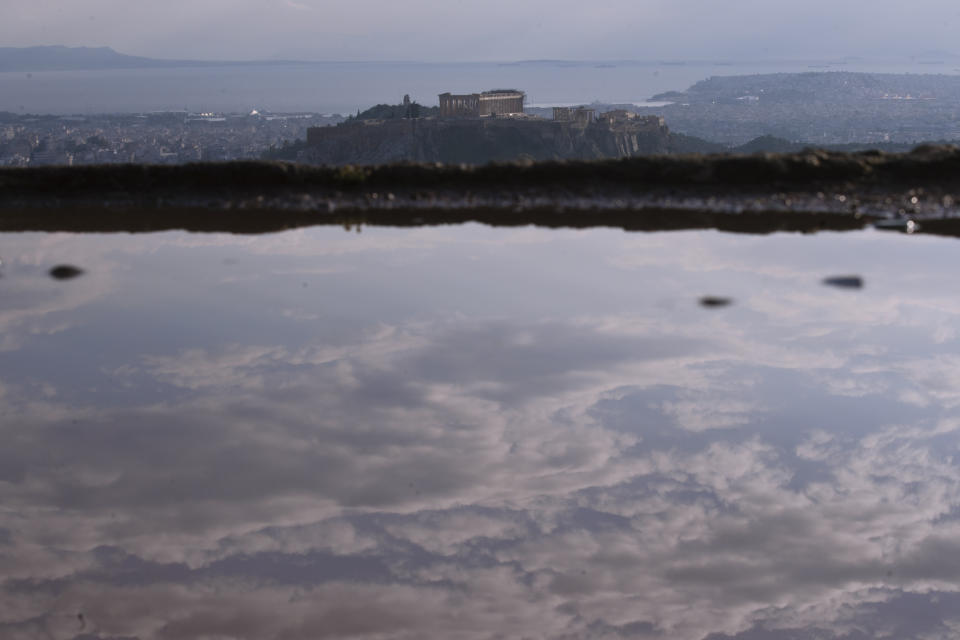 The sky is reflected in a puddle on Lycabettus hill as in the background is seen the city of Athens with the ancient Acropolis hill after a rainstorm, on Wednesday, April 17, 2019. A lightning bolt struck the Acropolis in Athens during a rainstorm Wednesday, lightly injuring two visitors and two guards but causing no damage to the country's most famous ancient site, Greek officials said.(AP Photo/Petros Giannakouris)