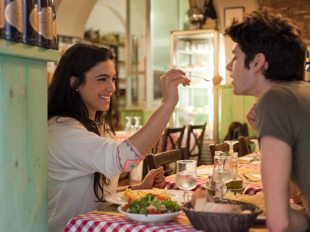 happy young couple eating together in restaurant
