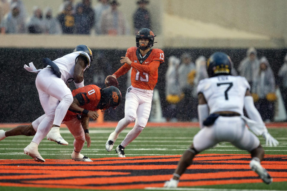 Oklahoma State running back Ollie Gordon (0) blocks West Virginia linebacker Lee Kpogba (8) for quarterback Garret Rangel (13) during the second half of the NCAA college football game in Stillwater, Okla., Saturday Nov. 26, 2022. (AP Photo/Mitch Alcala)