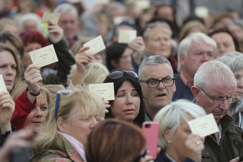 People read aloud names of children as they gather to protest at the site of the former Tuam home for unmarried mothers in County Galway, Sunday, Aug. 26, 2018. Survivors of one of Ireland's wretched mother and baby homes hold their own demonstration Sunday. The location is Tuam, site of a mass grave of hundreds of babies who died at a church-run home. (Niall Carson/PA via AP)