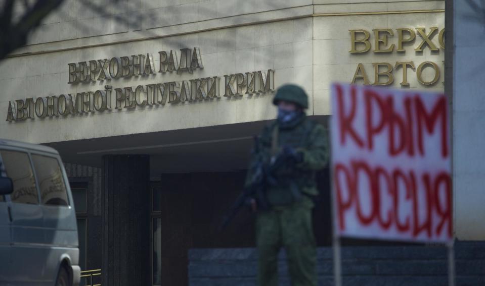 Unidentified gunmen wearing camouflage uniforms block the entrance of the Crimean Parliament building in Simferopol, Ukraine, Saturday, March 1, 2014. The discord between Russia and Ukraine sharpened Saturday when the pro-Russian leader of Ukraine's Crimea region claimed control of the military and police and appealed to Russia's president for help in keeping peace there. Signs on a wall read "Parliament of Crimean Republic" and poster at right reads "Crimea Russia". (AP Photo/Ivan Sekretarev)