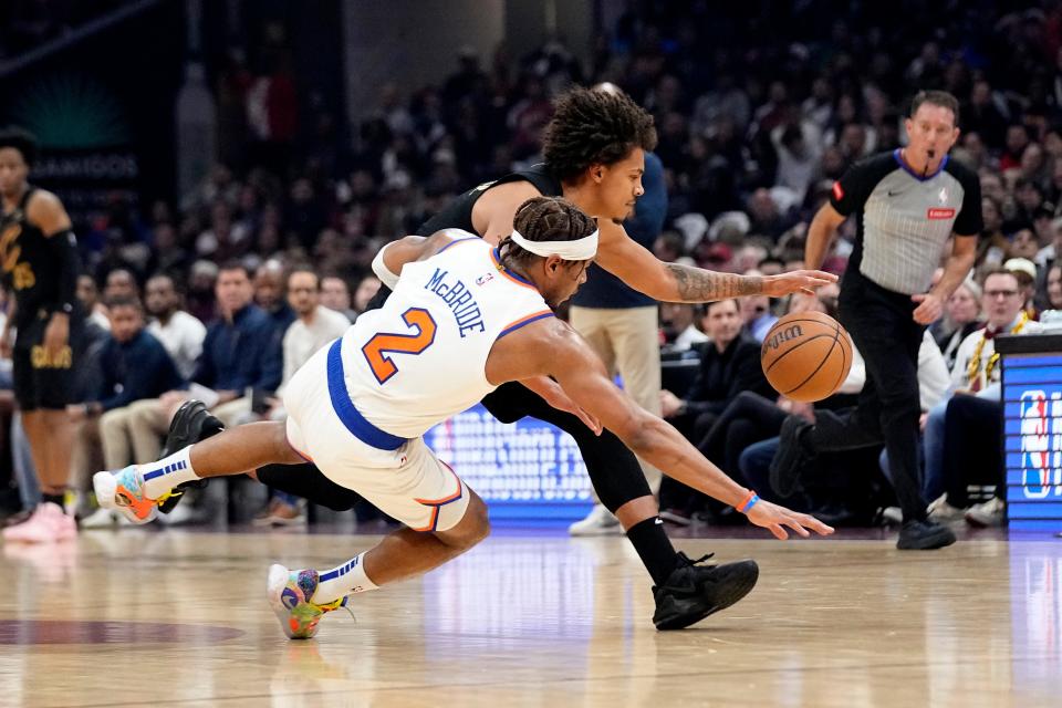 New York Knicks guard Miles McBride (2) and Cleveland Cavaliers guard Craig Porter, right, reach for the ball in the first half of an NBA basketball game, Sunday, March 3, 2024, in Cleveland. (AP Photo/Sue Ogrocki)