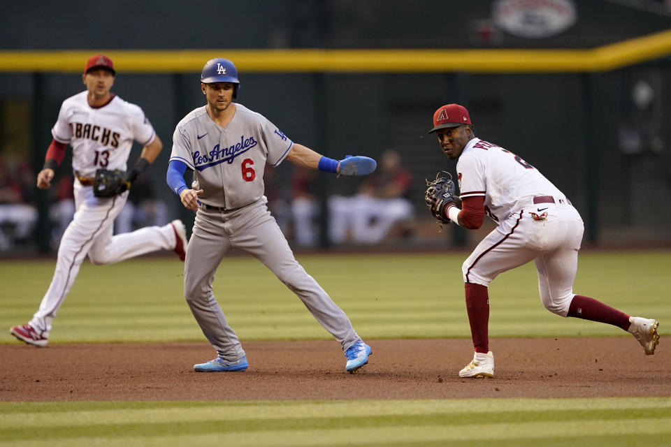 Arizona Diamondbacks Geraldo Perdomo, right, turns a double play on Los Angeles' Dodgers Justin Turner after tagging out Trea Turner (6) during the first inning of a baseball game, Monday, April 25, 2022, in Phoenix. (AP Photo/Matt York)