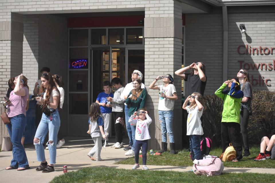 People gathered outside of the Clinton Township Public Library on Monday, April 8, 2024, to check out the solar eclipse during an eclipse public viewing party. Staff at the library greeted eclipse watchers younger and older for the party.