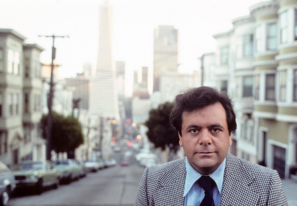 Paul Sorvino in a suit and tie standing on a street