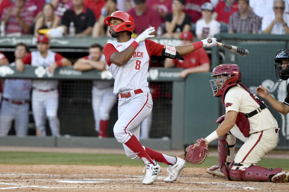 FILE - North Carolina State's Jose Torres (8) watches the ball after connecting for a home run against Arkansas in the ninth inning during an NCAA college baseball super regional game in Fayetteville, Ark., in this Sunday, June 13, 2021, file photo. Home runs — lots and lots of them — have defined the NCAA baseball tournament so far. A total of 381 have been hit in 123 games, the highest total through super regionals since at least 2005.(AP Photo/Michael Woods, File)