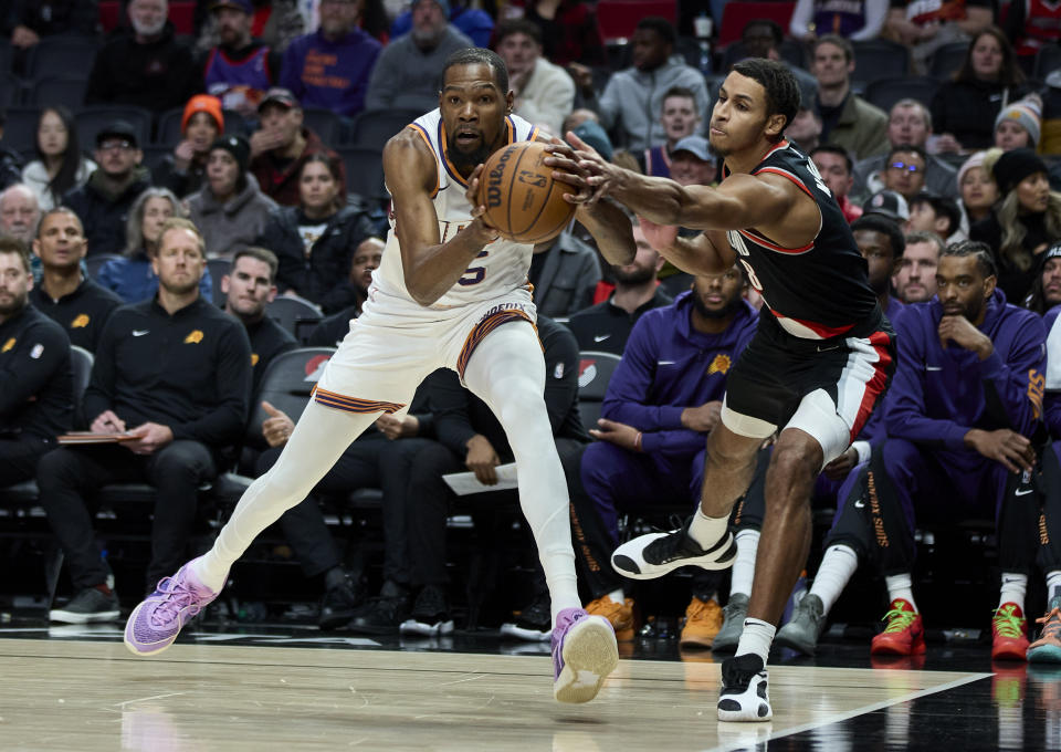 Phoenix Suns forward Kevin Durant, left, and Portland Trail Blazers forward Kris Murray, right, reach for the ball during the first half of an NBA basketball game in Portland, Ore., Sunday, Jan. 14, 2024. (AP Photo/Craig Mitchelldyer)