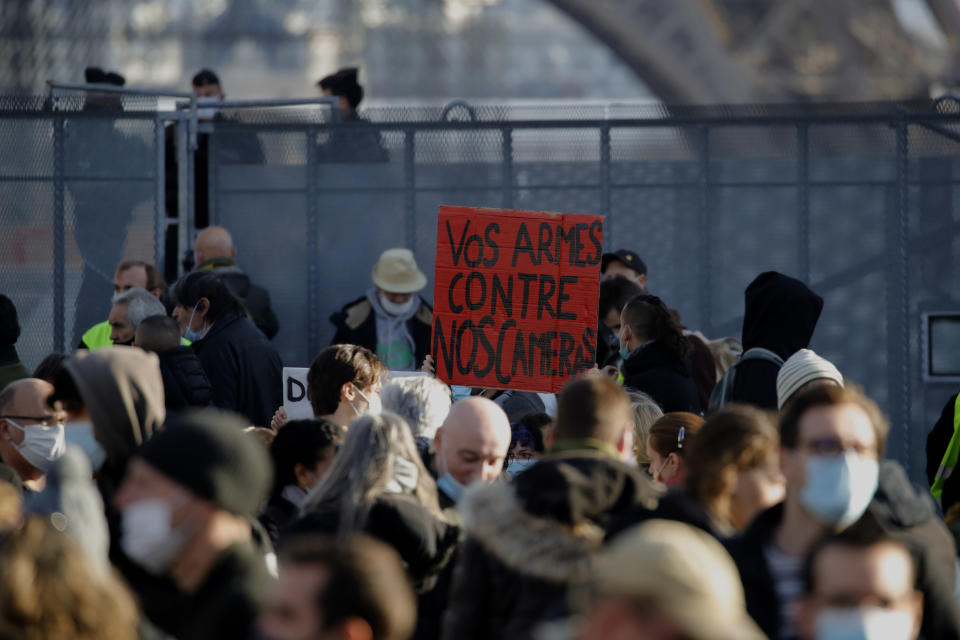 Demonstrators gather during a protest against bill on police images, in Paris, Saturday, Nov. 21, 2020. Thousands of people took to the streets in Paris and other French cities Saturday to protest a proposed security law they say would impinge on freedom of information and media rights. The board reads: Your guns against our cameras. (AP Photo/Christophe Ena)