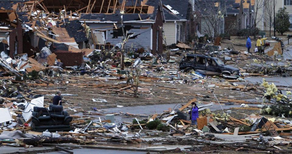 FILE - In this Jan. 23, 2012, file photo, residents walk around through the debris of their neighborhood after a tornado ripped through the Trussville, Ala. area. Storm chasers are watching the Southeast as a nasty storm brews with the potential to spin off a batch of tornadoes. Tornado season is just about here and forecasters believe twisters are possible Thursday and Friday. But in reality, it got an early and deadly start in late January when two people were killed by separate twisters in Alabama. The season usually starts in March and then ramps up for the next couple of months, but forecasting tornado seasons is even more imprecise than predicting hurricane seasons. (AP Photo/Butch Dill)