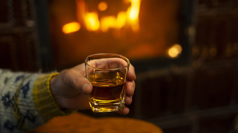 hand holding whiskey by fire