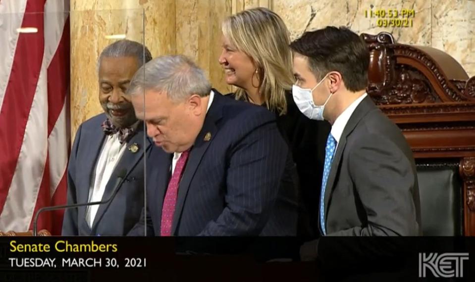 Senate President Robert Stivers signs his West End bill Tuesday night before celebrating with, from left, Sens. Gerald Neal, Julie Raque Adams and Morgan McGarvey of Louisville.