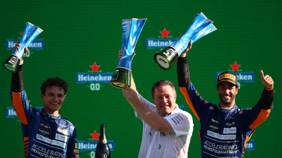 McLaren Racing's CEO Zak Brown shares the podium with Daniel Ricciardo and Lando Norris at the 2021 Italian Grand Prix, where Ricciardo and Norris finished first and second, respectively.