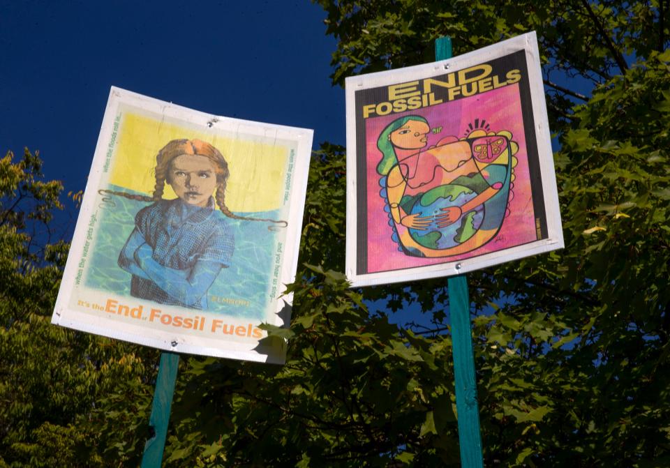 Signs lean against the trees at the Wayne Morse Free Speech Plaza in Eugene as part of a protest to end the era of fossil fuels.